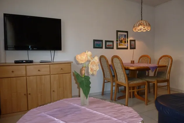 Wohn- und Essbereich der Monteurwohnung in Pohlheim mit Esstisch, Stühlen und Wand-TV